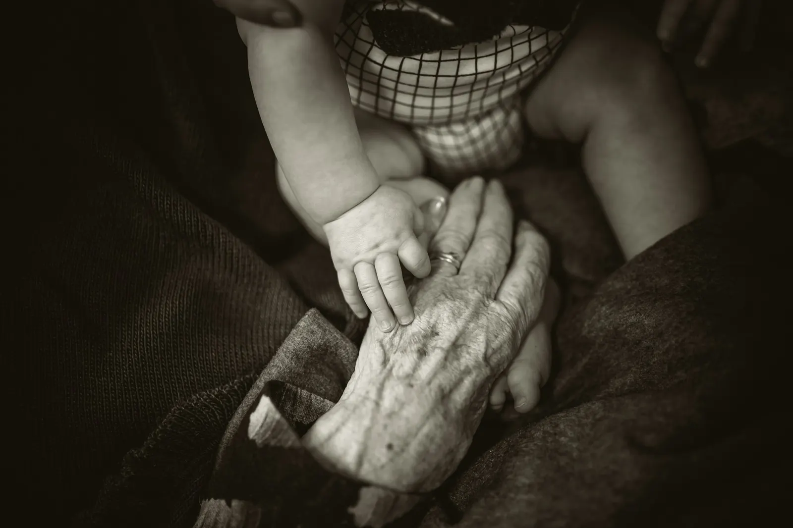 A baby's hand resting in a grandmother's hand, in black and white