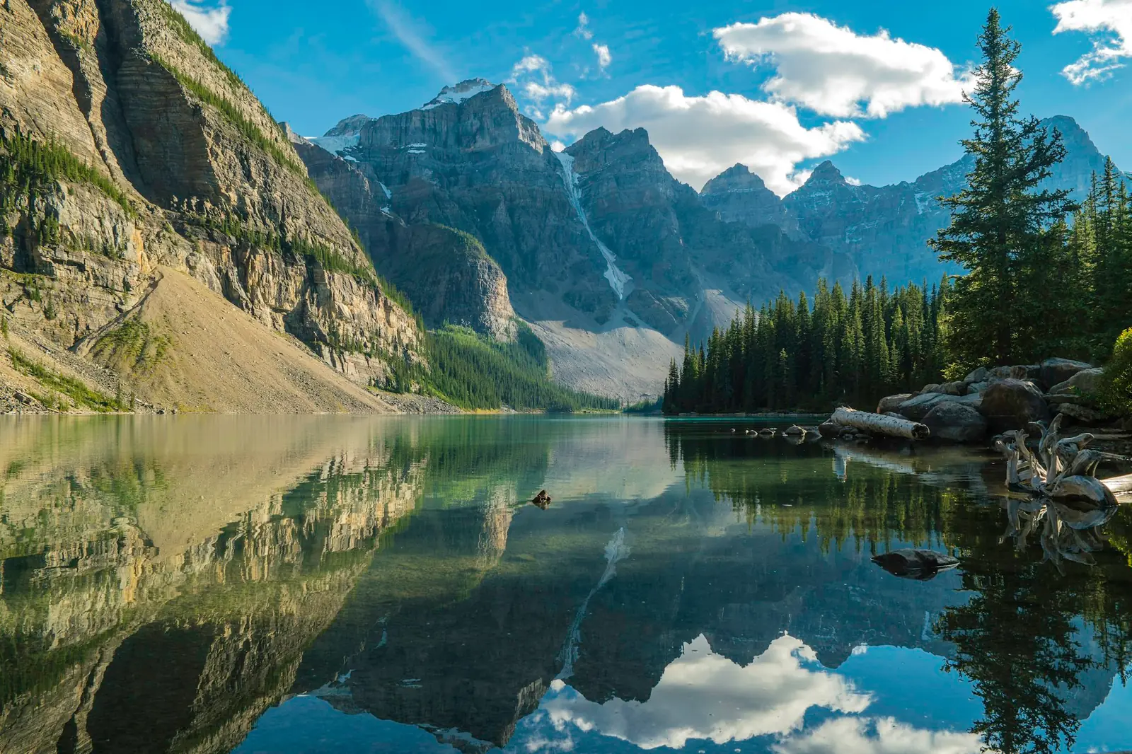 A mountain range and pine trees reflected in a clear alpine lake